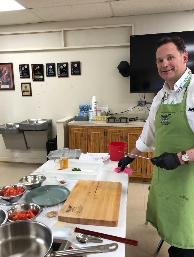 Lodge member in green apron at the cooking demonstration